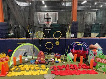 Party equipment staged on the turf at JPLEX: goals, hoops, cones, balls and game gear